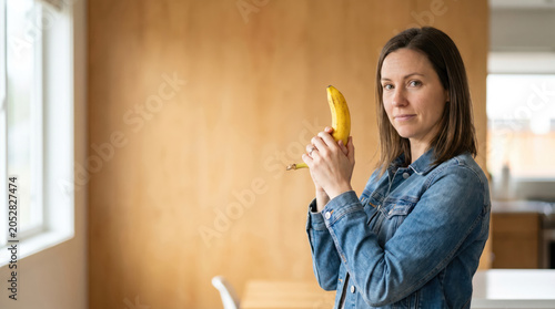 Smiling Woman Holding Banana Like a Toy Gun