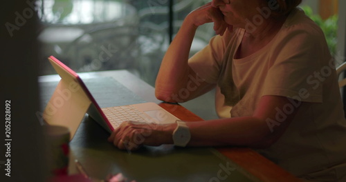 Bild auf Leinwand Elderly woman concentrating on laptop screen while working or browsing at home d