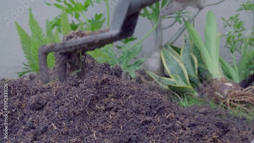 Mixing soil with fertilizer using a hand shovel and a hand fork close up, agriculture.