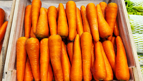 Obraz na płótnie A top-down shot of fresh, bright orange carrots arranged neatly in a wooden crate at a supermarket display counter