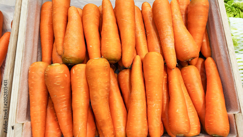 Fotografía A top-down shot of fresh, bright orange carrots arranged neatly in a wooden crate at a supermarket display counter