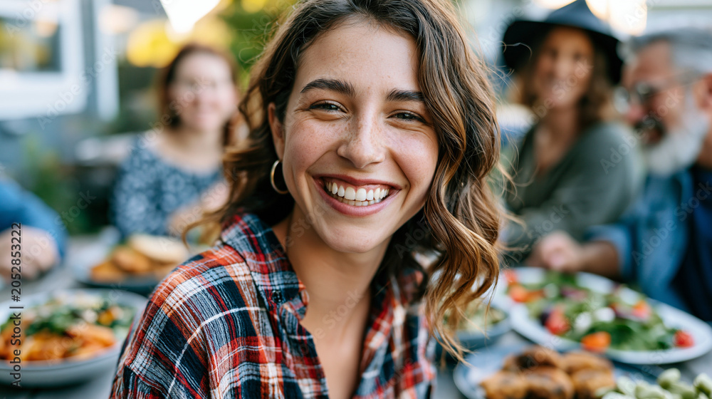 Fototapeta premium Moroccan au pair and a suburban American family share a Sunday meal at a backyard picnic table, the cultural exchange visible through the mix of dishes on the table and the easy laughter bridging na