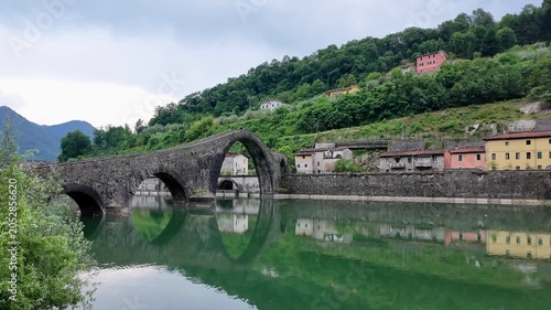 The devil's bridge or Maddalena Bridge, is a historic stone bridge with unique arches, beautifully reflected in the calm green waters of the Serchio River in Borgo a Mozzano, village of Tuscany