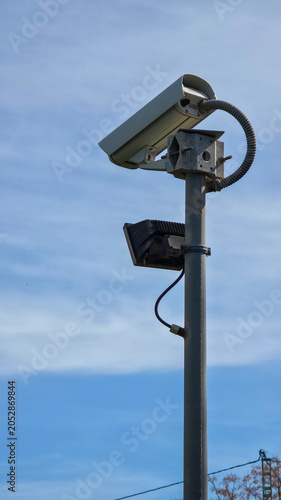 Security camera monitoring urban area against blue sky