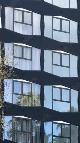 Modern building facade with geometric windows reflecting trees