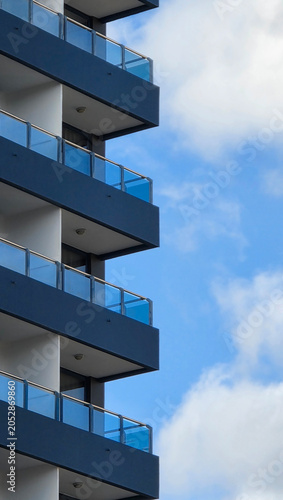 Modern building balconies with glass railings against blue sky