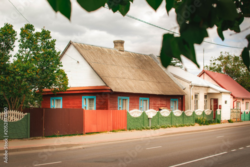 Bild auf Leinwand red wooden house with blue windows and fence on residential street