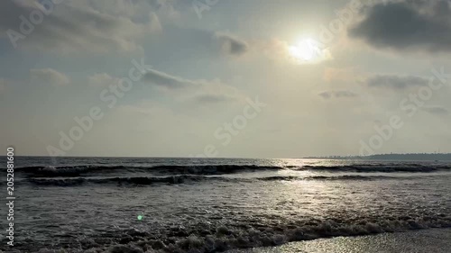 Serene hazy sunset over calm ocean waves and cloudy sky