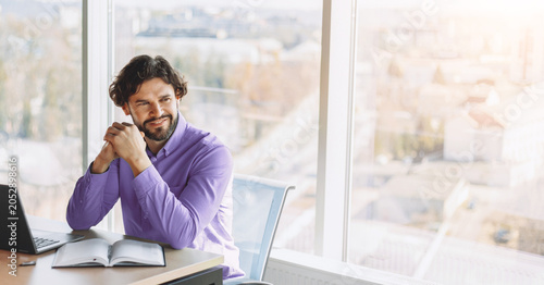 Canvas Print A man sits at a desk with a laptop and notebook