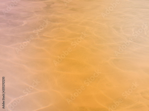 Warm atmospheric pool water background showing realistic sun caustics over an orange and terracotta field