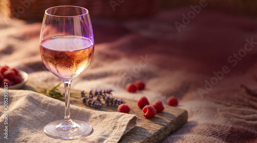 Rosé wine glass with fresh raspberries and lavender on wooden table  