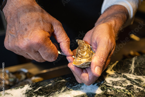 Foto Close-up of a Chef Shucking Fresh Oyster with a Shucking Knife