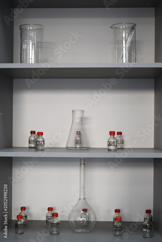 Laboratory shelves with chemical containers, glassware and scientific equipment. Concept of chemistry education, scientific research, laboratory organization and academic science.
