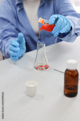 Chemical solution being added to laboratory flask during educational chemistry experiment. Scientific testing, laboratory analysis and biotechnology research concept with copy space.back to school.