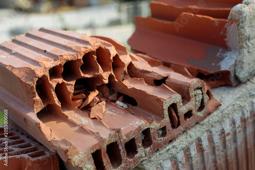 Broken red ceramic hollow bricks stacked on a construction site reveal their inner honeycomb structure in sharp close-up detail