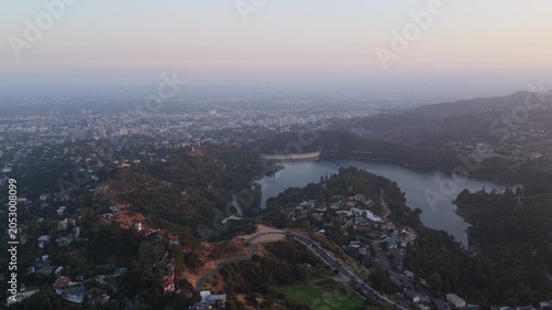 Hollywood Reservoir panorama over Los Angeles during a hazy morning, capturing the city skyline, urban sprawl, and surrounding hillsides under a soft, glowing light