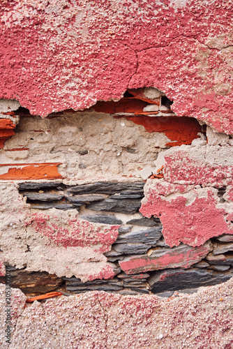 détail coloré de texture sur un mur décrépi de la façade d'une vielle maison en béton et briques rose