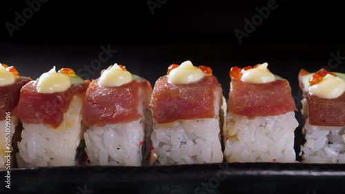 Sushi rolls with tuna on black platter and dark background. Closeup
