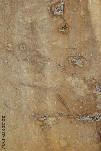 détail de texture sur un mur décrépi ocre et marron de la façade d'une vieille maison en béton 