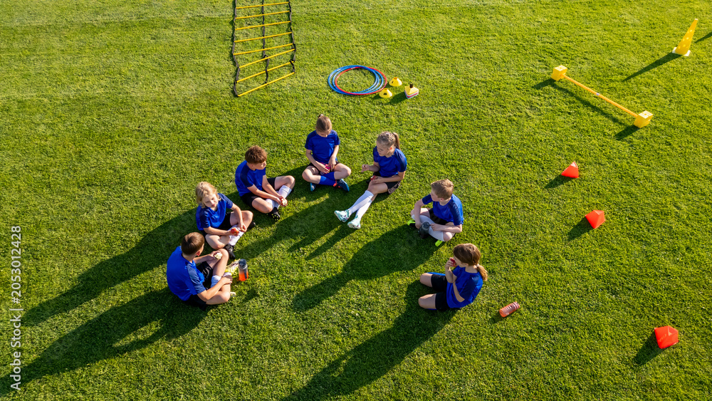 Naklejka premium Young soccer players taking break during football practice on sports field.