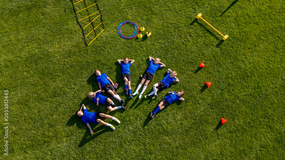 Naklejka premium Young soccer players taking break during football practice on sports field.