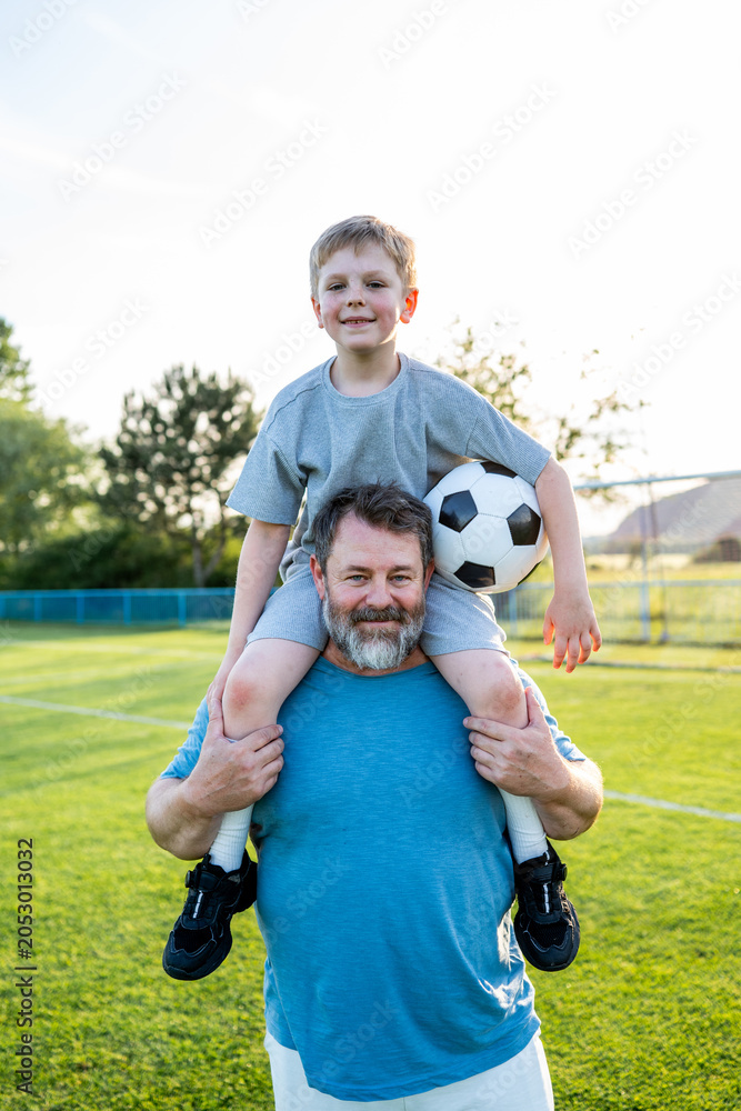 Obraz premium Dad and son sharing passion for football and active lifestyle.