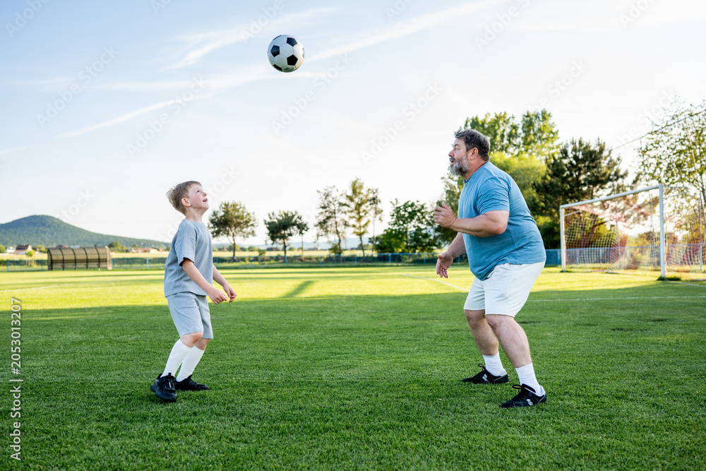 Obraz premium Father teaching son football skills during training on sports field.