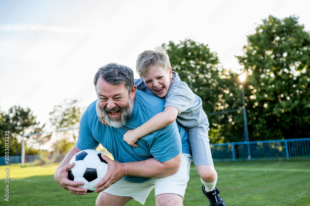 Obraz premium Dad and son sharing passion for football and active lifestyle.