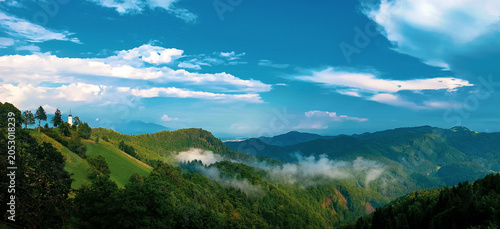 Tableau sur toile A breathtaking aerial panorama reveals rolling mountain valleys, green forests and dramatic cloud formations across Slovenia