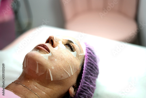 Foto Woman receiving facial sheet mask for skin treatment
