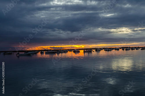Fotografía Coucher de soleil dramatique sur un plan d’eau calme sous ciel nuageux