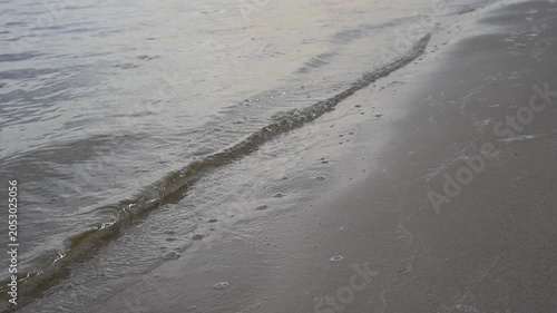 Real-time 8s static shot of water ripples washing onto a sandy shore. Close-up on sand texture, ideal for spa, wellness, and travel backgrounds.
