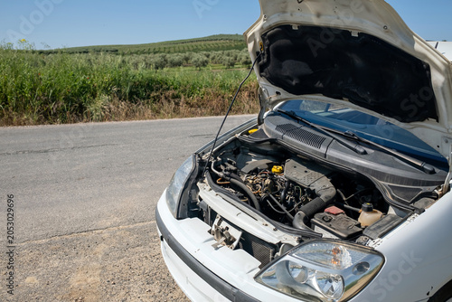 Fotografia Vehicle stopped on the side of a rural road, engine visible under an open hood,