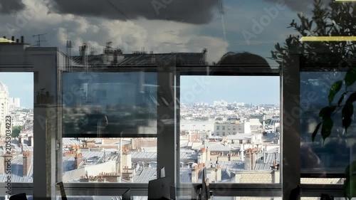 Espace de bureau moderne avec vue panoramique sur les toits de Paris à travers une baie vitrée