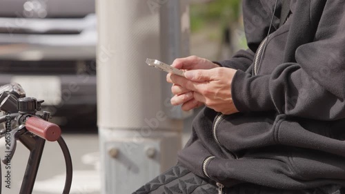 Slow motion Japanese man sits on a bicycle while using a smartphone on an Osaka city street, showing urban mobility, technology, travel and everyday lifestyle in Japan