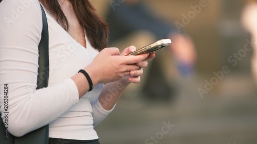 Slow motion Taiwanese woman uses her smartphone on a Taipei street, showing modern communication, urban lifestyle, daily mobility and everyday technology in Taiwan