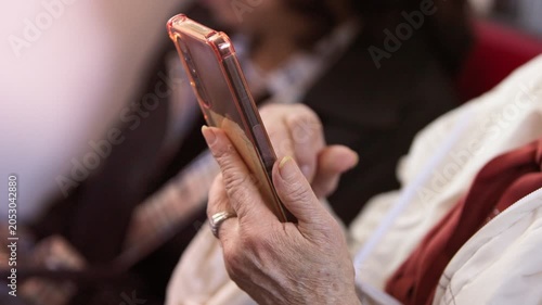 Slow motion senior Taiwanese woman uses a smartphone inside the metro, showing older adult adaptation to new technology, digital communication, public transportation and city life