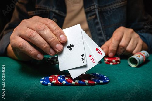 Fotografi Three playing cards with aces are held above stacks of colorful poker chips