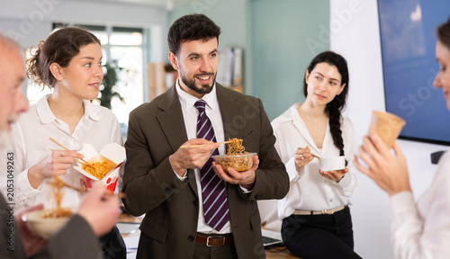 Bild auf Leinwand Group of friendly young office workers different ages standing and eating fast f