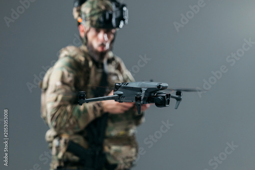 фотографія Military serviceman piloting UAV drone using handheld controller in indoor environment