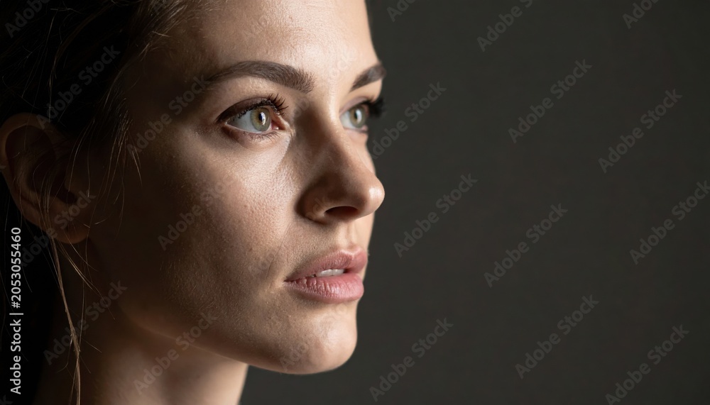 Fototapeta premium Close-up portrait of a woman with natural green eyes and clean skin. Beauty, authenticity, healthy face, pure look, real people, skincare and cosmetic advertising for editorial and commercial use.