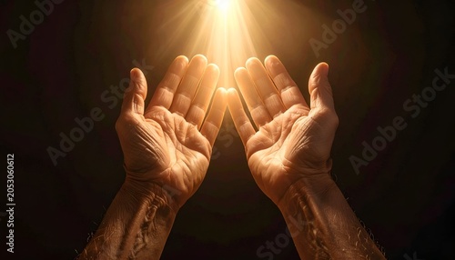 Upward facing hands bathed in golden light, emerging from darkness