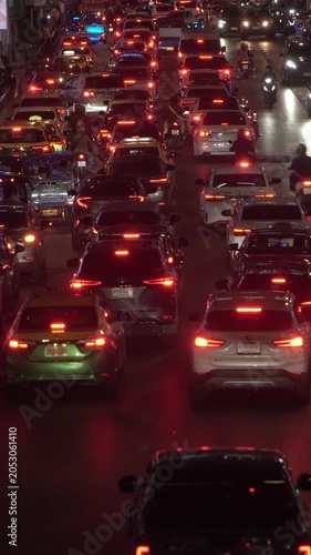 Timelapse of night traffic jam in Bangkok, Thailand, during rush hour in downtown. Capturing the motion of car tail lights and red stop signals, with vehicles moving through the cityscape.