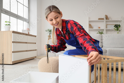 Young woman measuring furni...