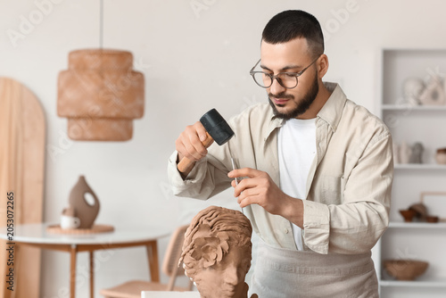 Young male sculptor chiseli...