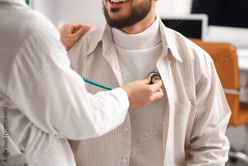 Female doctor with stethoscope listening to patient in clinic
