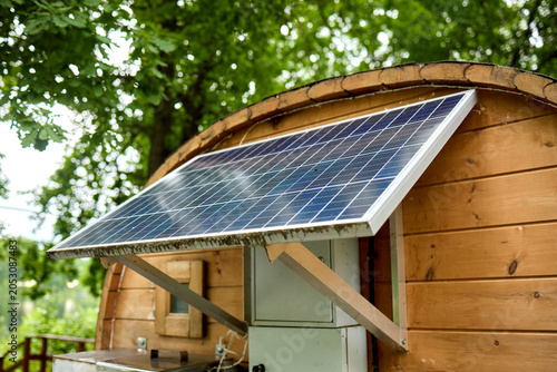 Solar panel mounted on wooden garden shed with leafy background