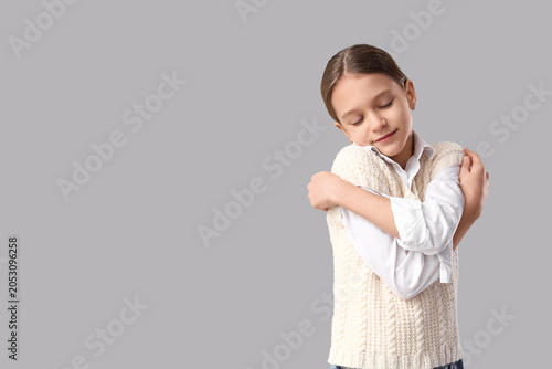 Cute girl hugging herself o...