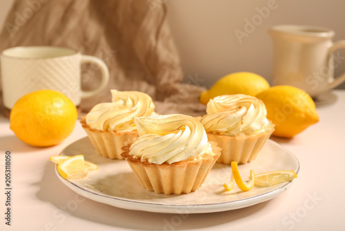 Fotografi Plate with delicious lemon tartlets on beige table