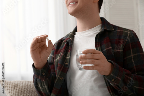 Young man taking pills at h...